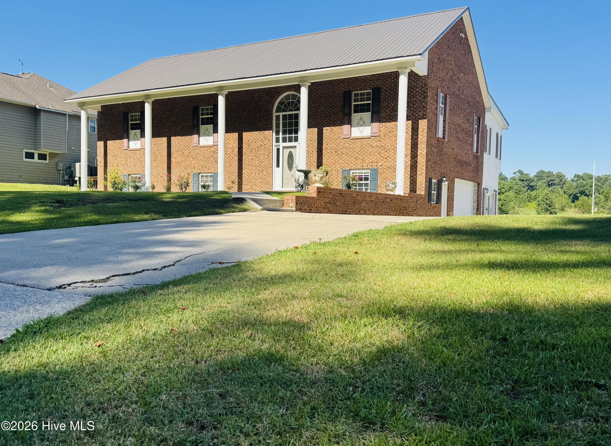 Angled front view of 888 Sea Gate Drive showing the curved concrete driveway leading to the covered porch and the attached side garage