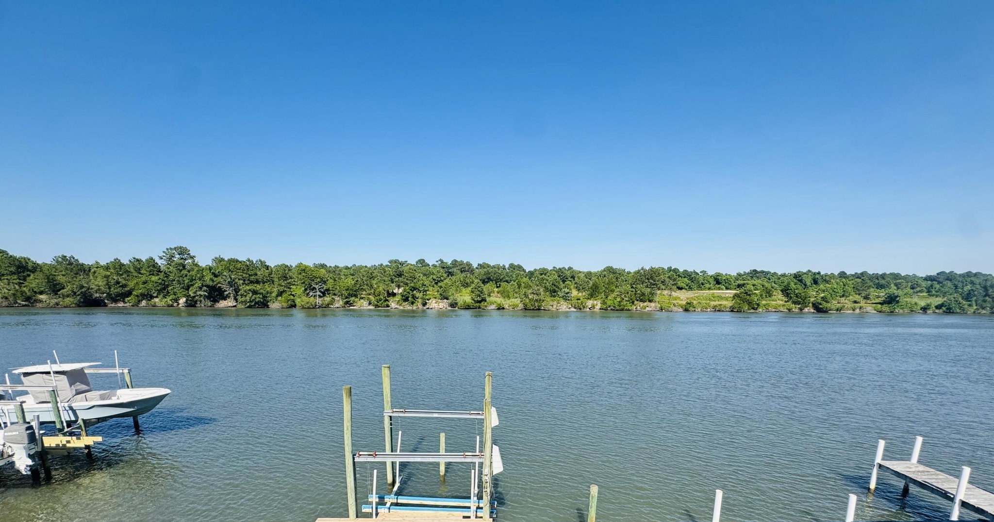 A private boat dock and metal boat lift extending into the Intracoastal Waterway off 888 Sea Gate Drive, with a powerboat raised on a neighboring lift and a tree-lined far shore
